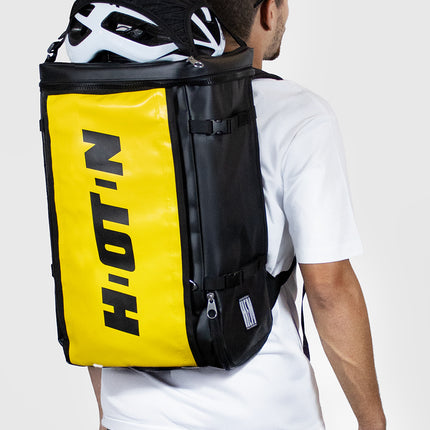 uomo con zaino da trasferta per ciclista giallo e casco fuori